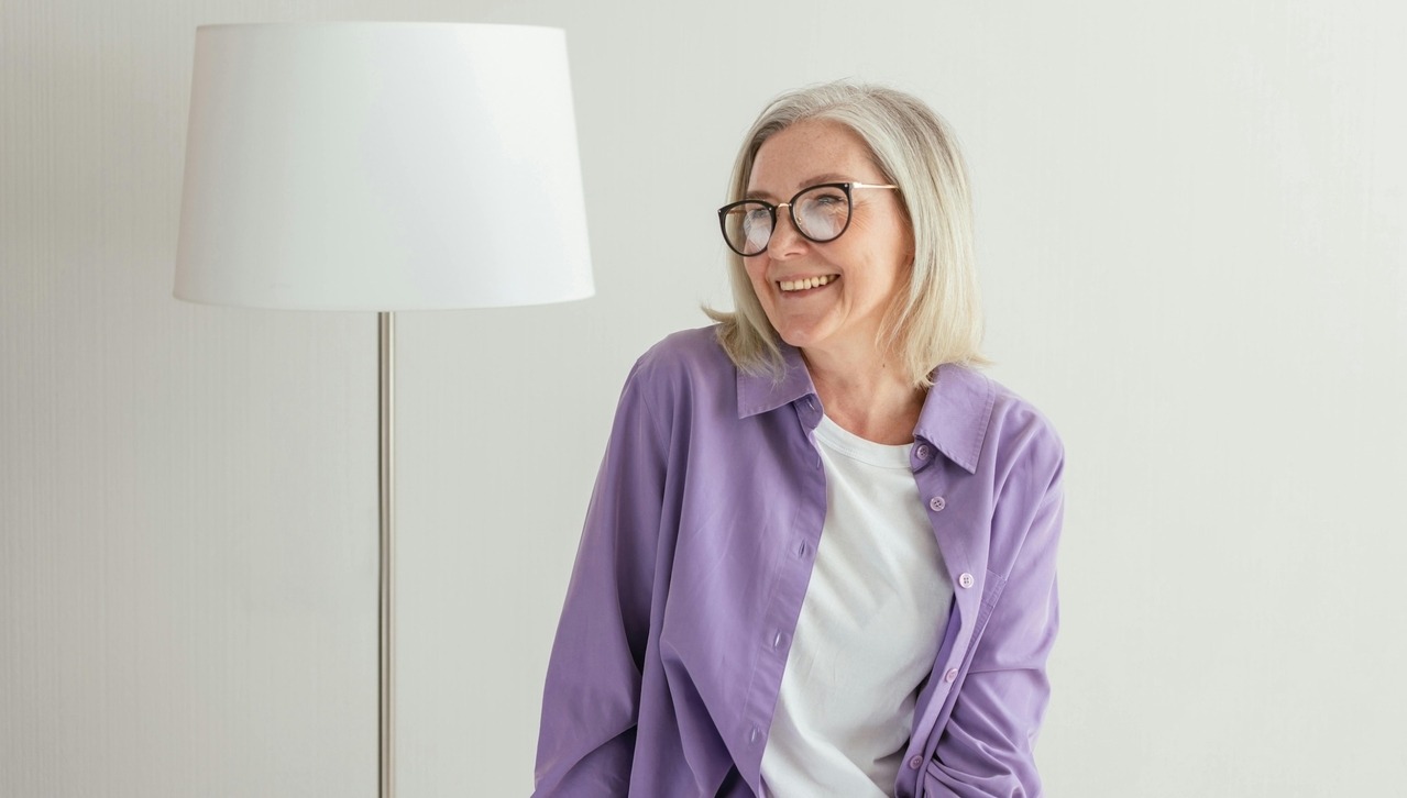 smiling older woman with white background and white lamp