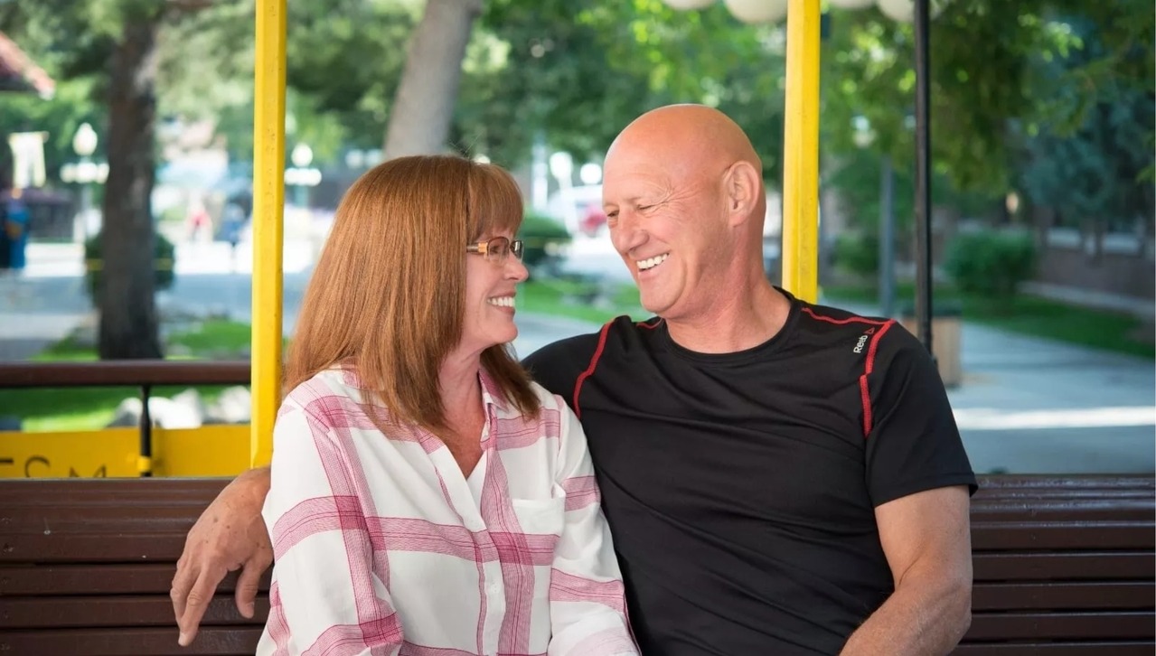 couple smiling at each other on bench